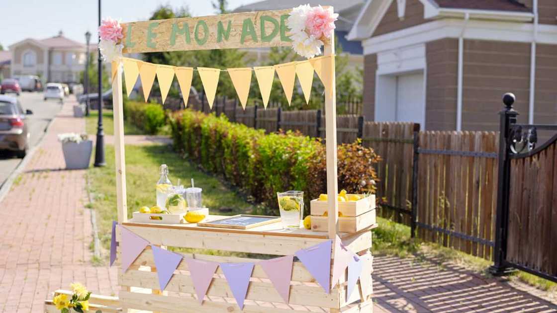 Fresh lemons in boxes and jugs with homemade lemonade on wooden stall Fresh lemons in boxes and jugs with homemade lemonade on wooden stall