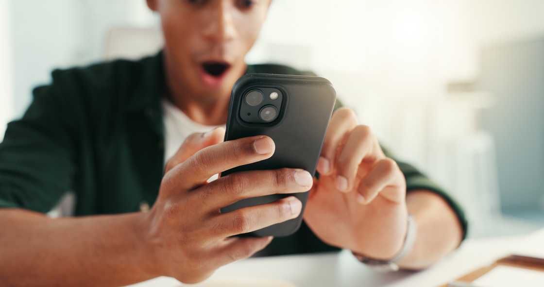 Person reacts with surprise while looking at a smartphone.