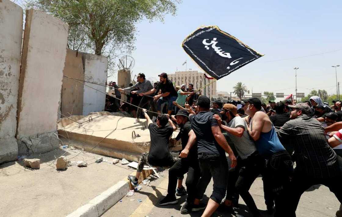 Sadr supporters tear down a concrete barrier before breaching the Green Zone