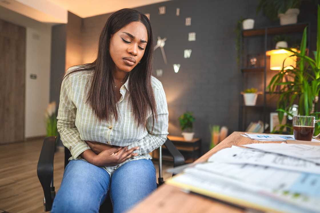 A young black woman is experiencing stomach pain