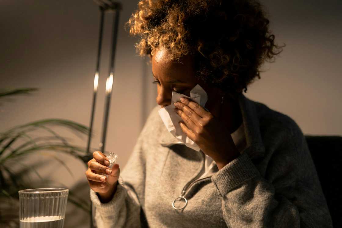 A woman wipes tears from her face with a tissue.
