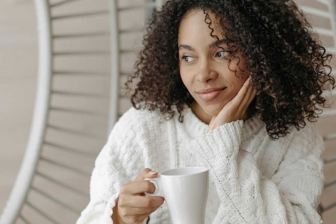 A happy woman reflecting on her life as she hold a cup of tea