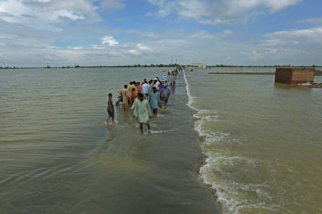 People walk along a flooded road to escape their villages in Punjab province People walk along a flooded road to escape their villages in Punjab province