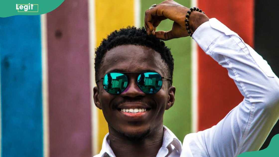 A young man smiling while touching his hair