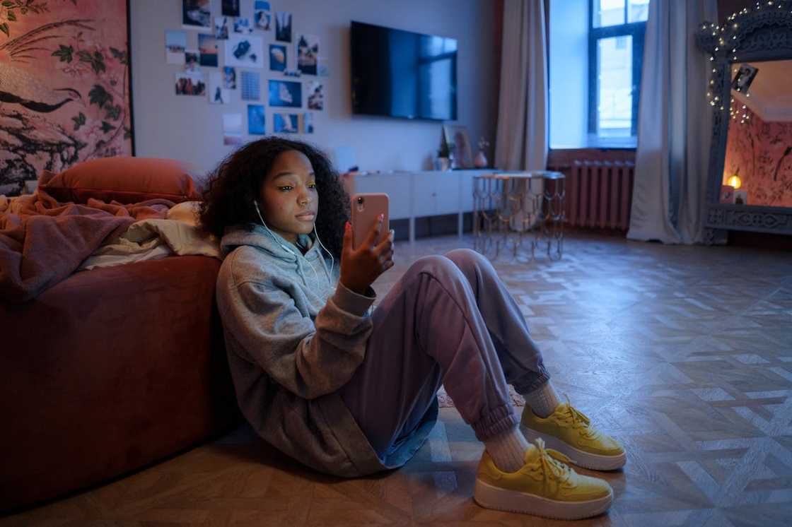 A young girl scrolls through her smartphone in the bedroom.