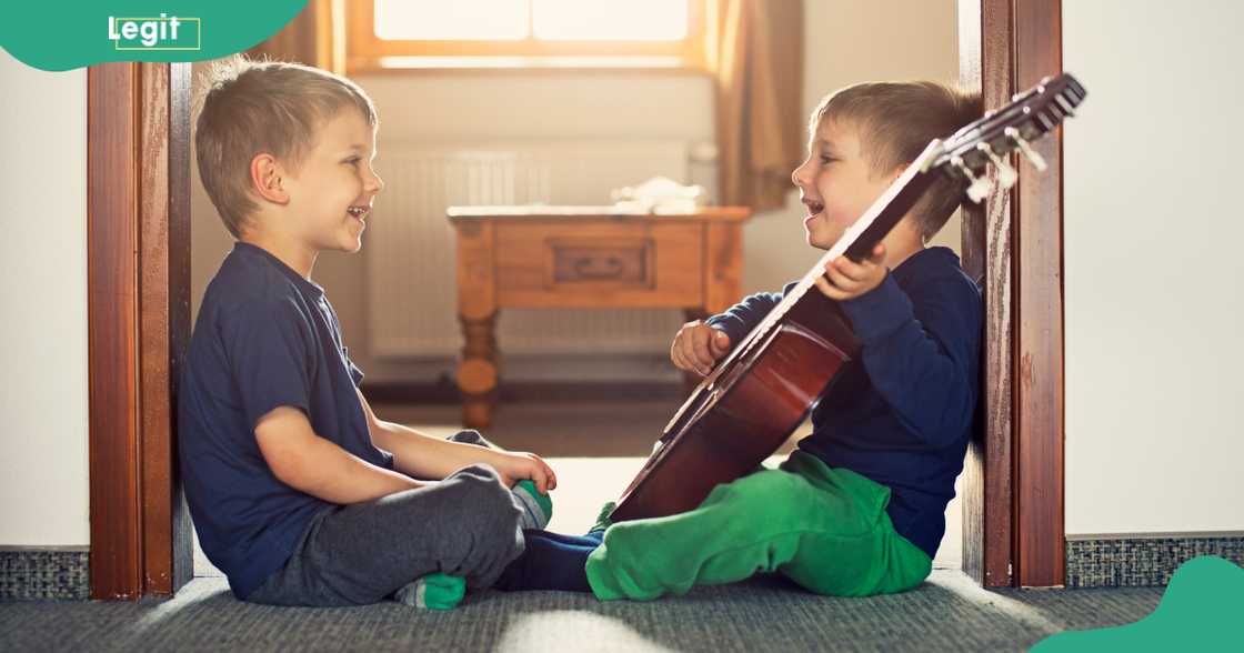 Two brothers sit facing each other while singing.