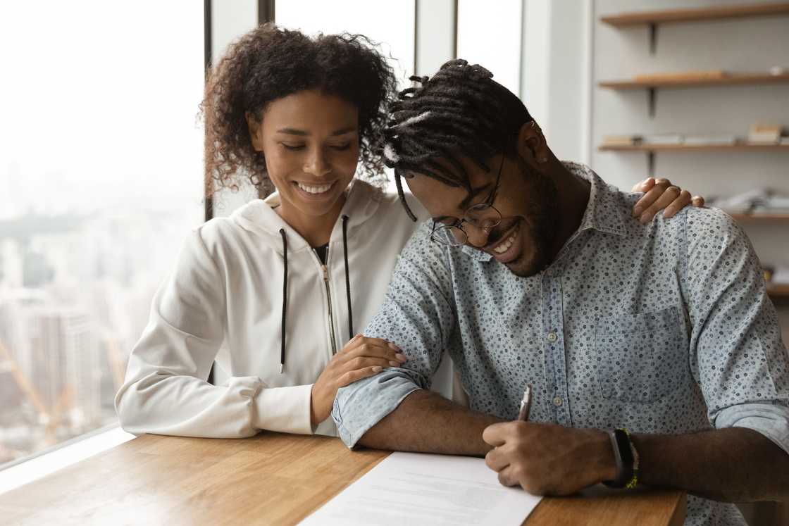 Couple sitting at a table signing a document Couple sitting at a table signing a document