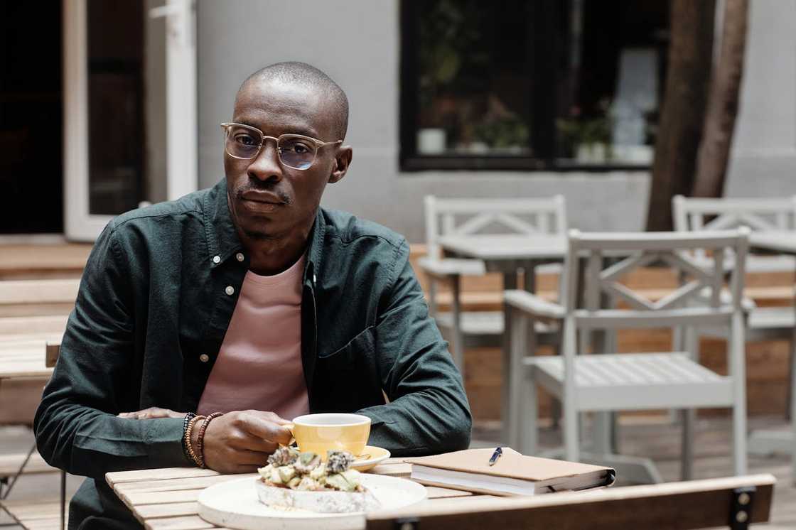 A man sits at an outdoor café table. A man sits at an outdoor café table.