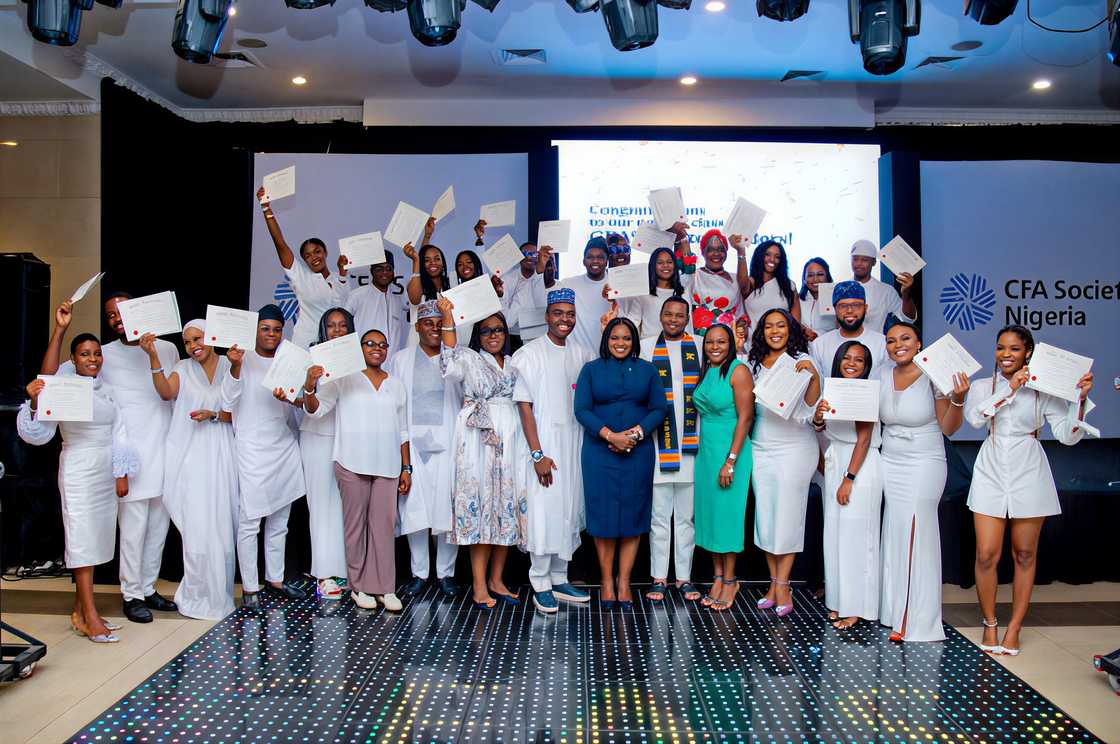 A group of young professionals raise certificates during a Charter recognition ceremony