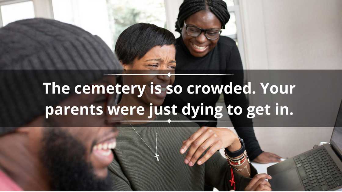 A man and two ladies are laughing as they look into a laptop screen