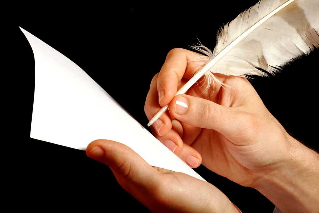 A hand writing with a feather pen A hand writing with a feather pen