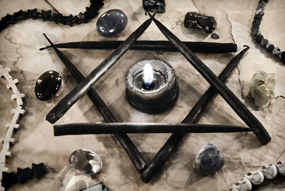 Pentagram symbol made of black candles with crystal stones on paper. Pentagram symbol made of black candles with crystal stones on paper.