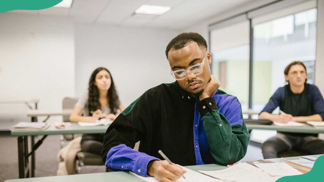 A male student takes notes in class