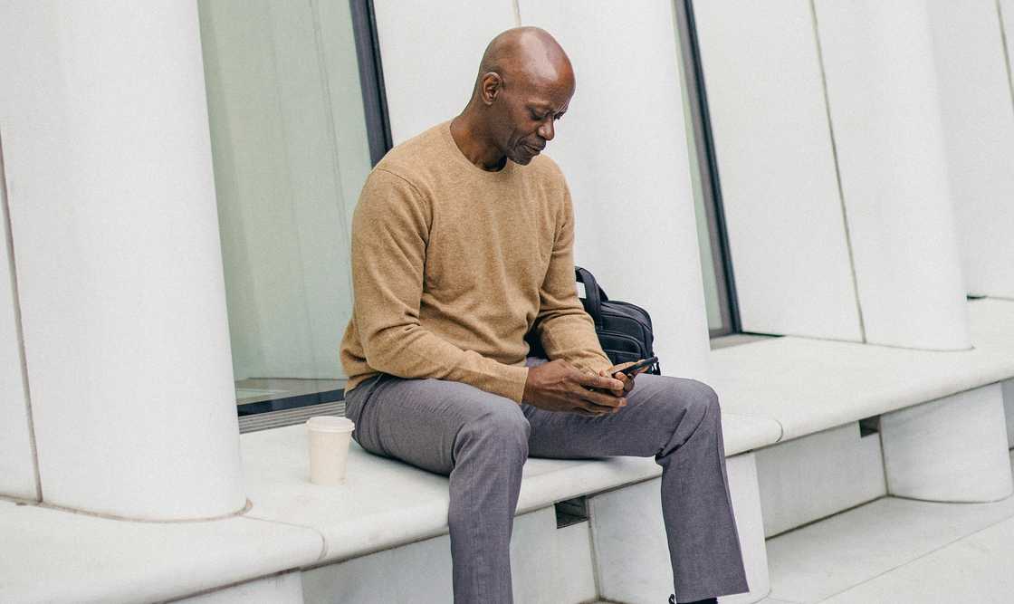 A man sitting on a bench using his smartphone