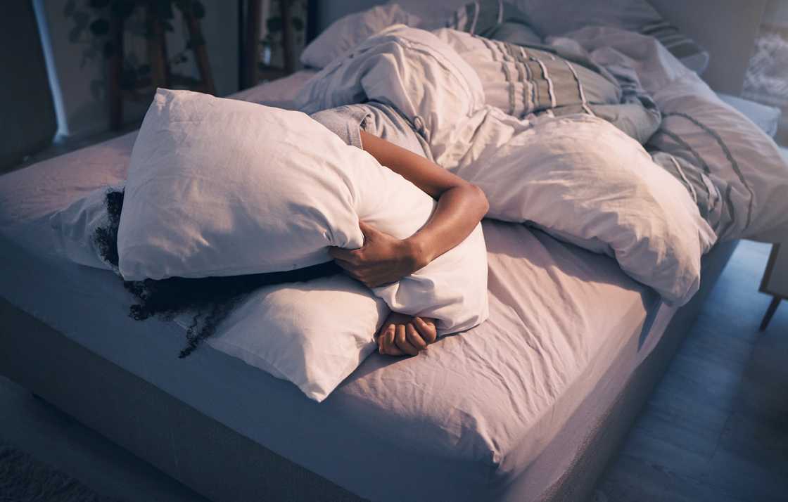 A woman lying in bed with pillow on her face