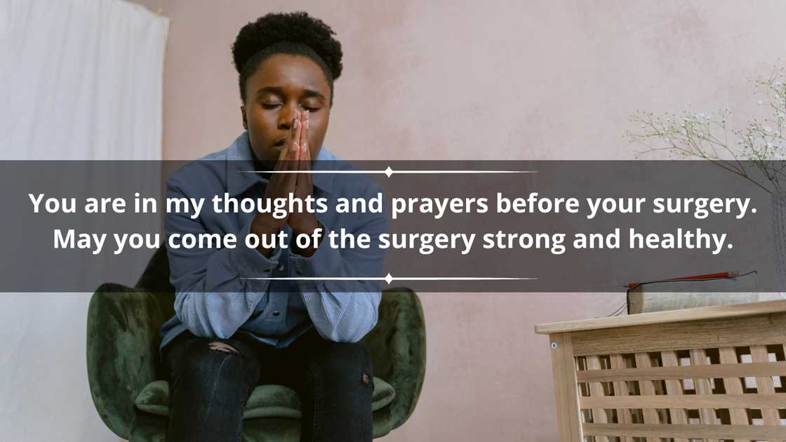 A young woman in a blue shirt and black denim pants is praying as she sits