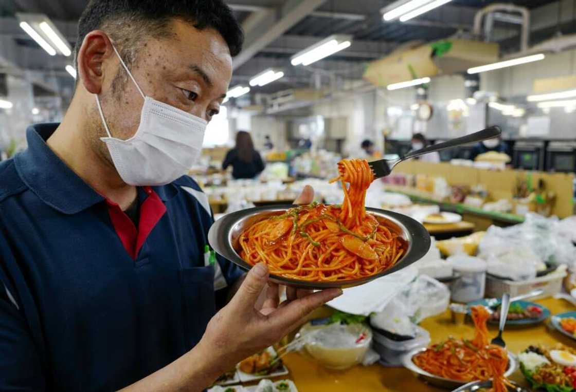 A fork stands suspended in mid-air, strands of 'spaghetti' dangling, as factory head Hiroaki Miyazawa checks a finished plastic food sample A fork stands suspended in mid-air, strands of 'spaghetti' dangling, as factory head Hiroaki Miyazawa checks a finished plastic food sample