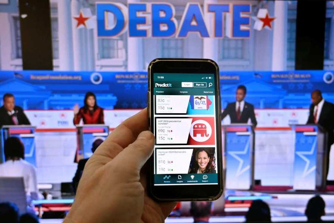 This photo illustration taken in Washington on November 1, 2023, shows a phone screen displaying PredictIt, one of two legal online prediction markets for US political gamblers