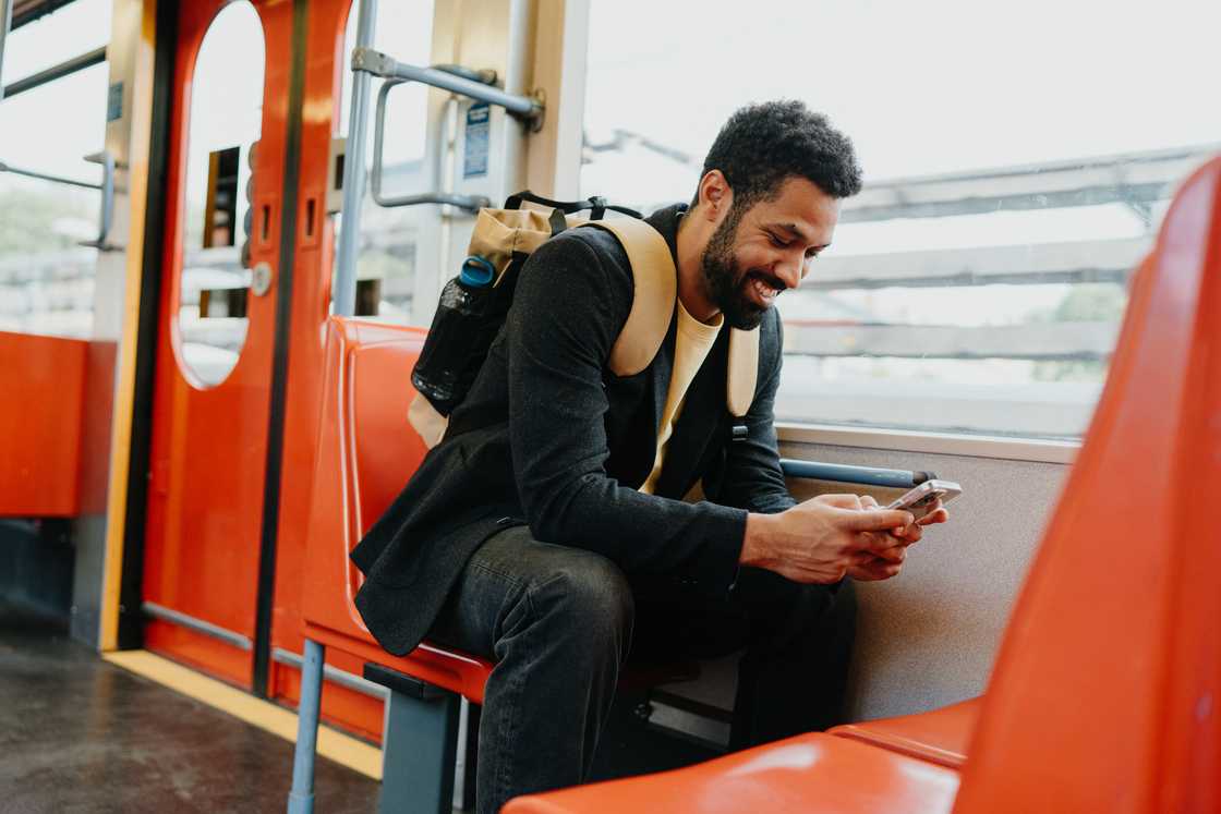 A smiling man scrolling on a smartphone A smiling man scrolling on a smartphone