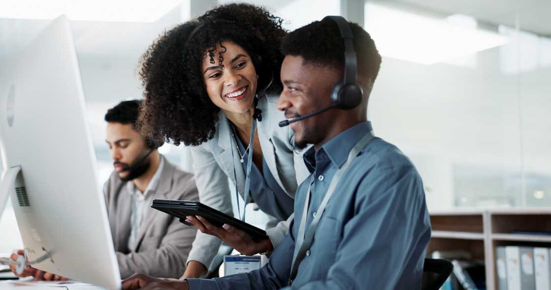 Call centre agents smile and chat between calls on the production floor.