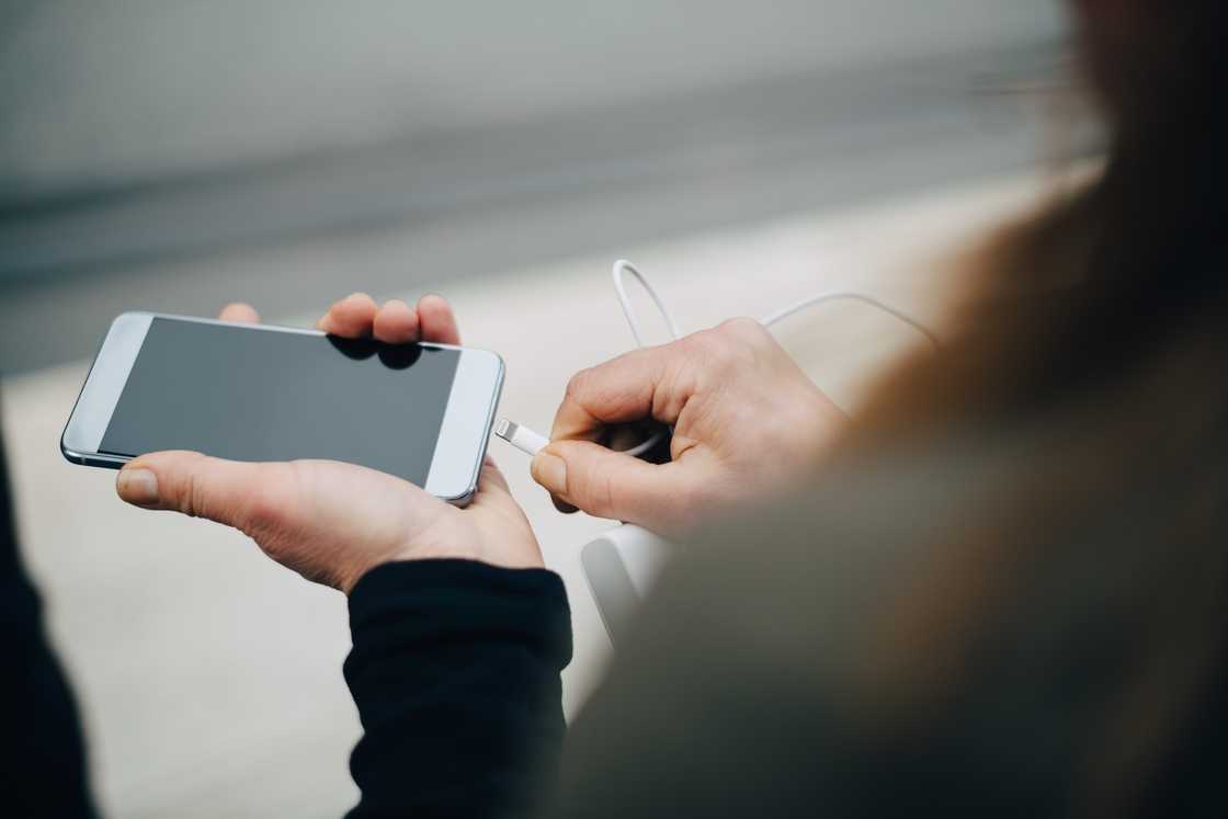 Cropped image of mature businesswoman inserting USB cable in smart phone. Cropped image of mature businesswoman inserting USB cable in smart phone.
