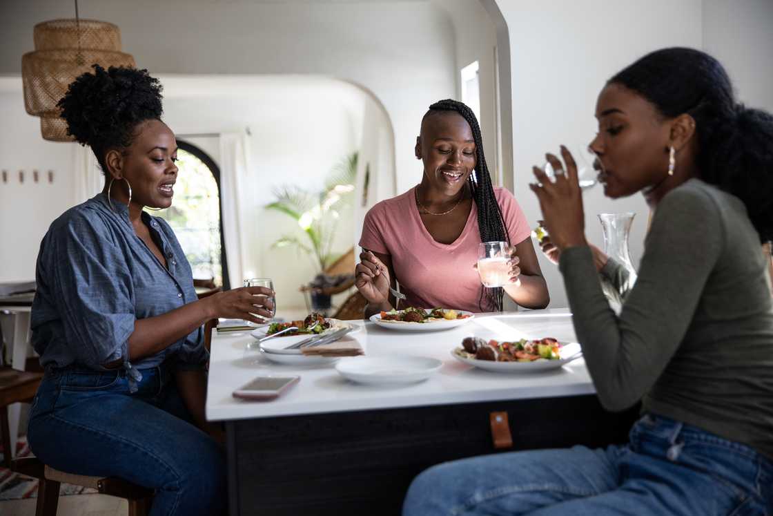 Three people sit around a dining table enjoying a meal together. Three people sit around a dining table enjoying a meal together.