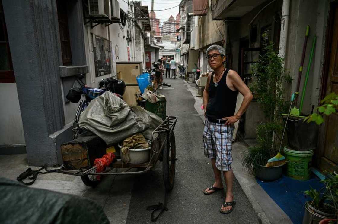 A man looks on in an alley as other Laoximen residents move furniture out of their soon-to-be-demolished homes A man looks on in an alley as other Laoximen residents move furniture out of their soon-to-be-demolished homes
