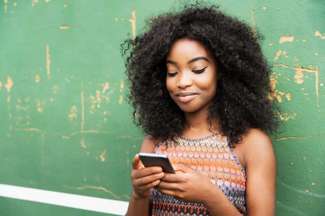 A woman using smart phone next to green wall