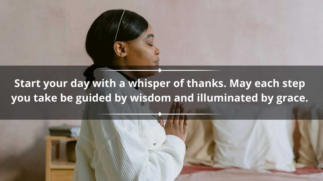 A woman in a white top is praying beside her bed