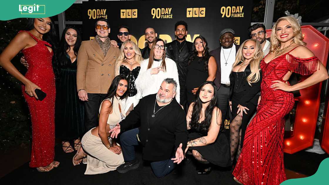 A large group of men and women dressed in formal black, red, and gold outfits pose together in front of a 90 Day Fiancé and TLC backdrop. A large group of men and women dressed in formal black, red, and gold outfits pose together in front of a 90 Day Fiancé and TLC backdrop.