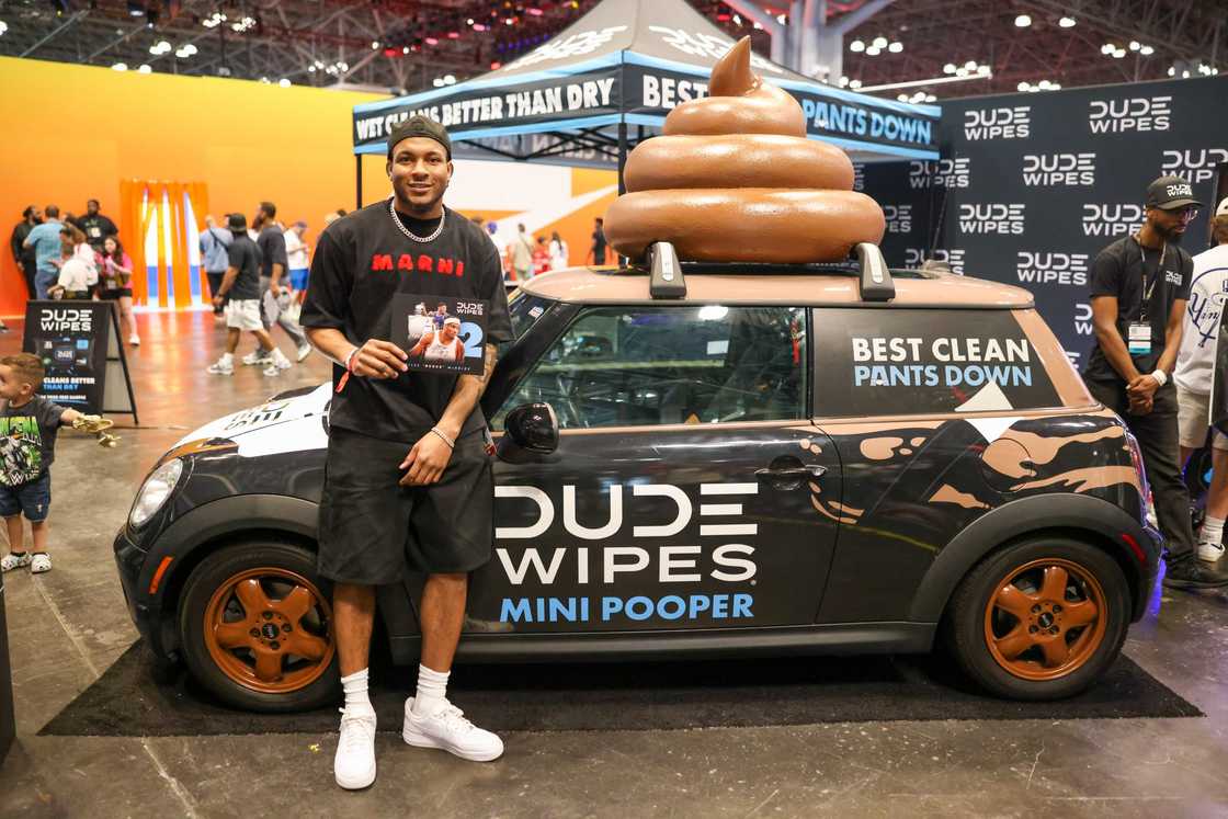 A guy posing next to a Dude Wipes branded car