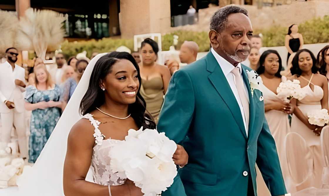 Simone Biles holds her bouquet as she walks down the aisle with her father, Ronald Biles. Simone Biles holds her bouquet as she walks down the aisle with her father, Ronald Biles.
