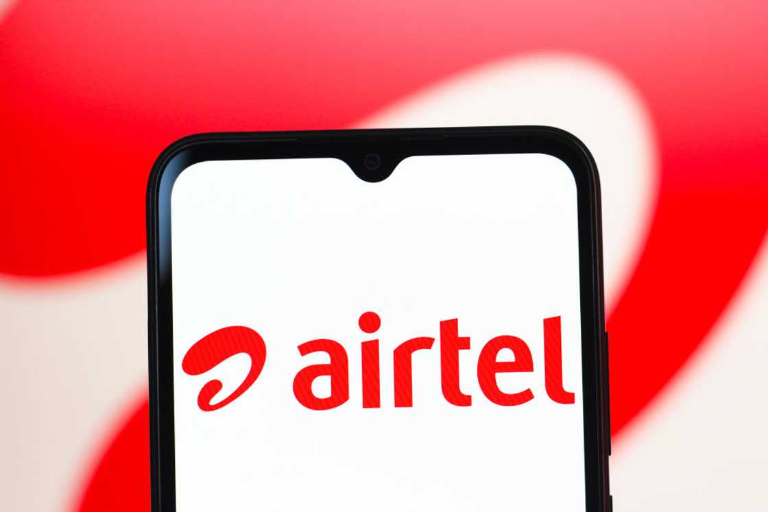 A close-up of a smartphone showing the red Airtel logo on a white screen. A close-up of a smartphone showing the red Airtel logo on a white screen.