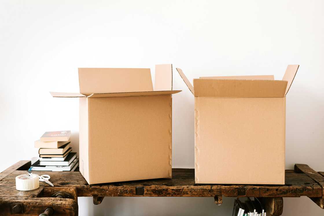 Cardboard boxes beside a stack of books on a wooden surface