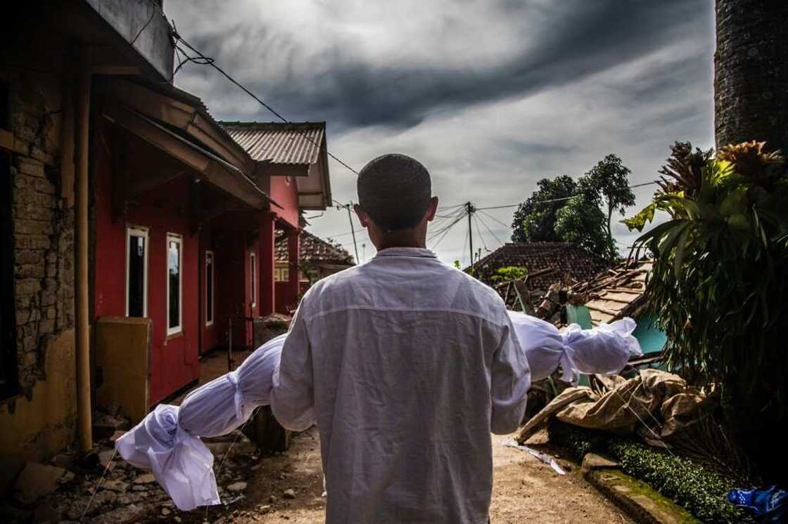 A villager carries the body of his dead son following a 5.6-magnitude earthquake in West Java