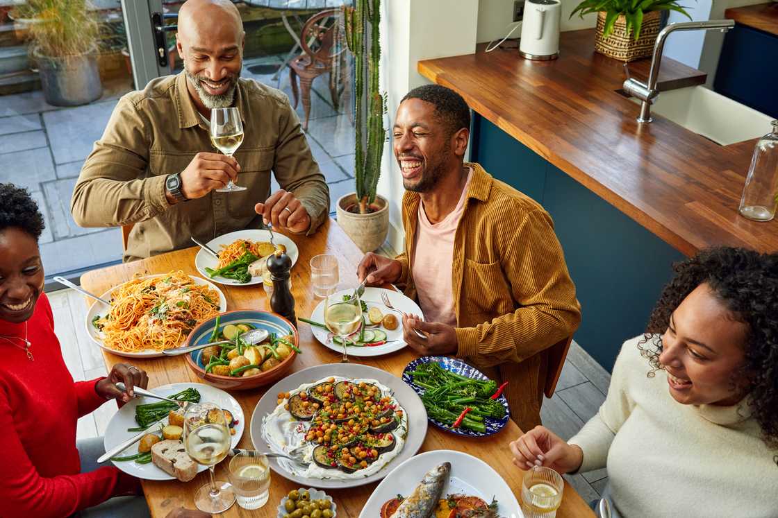A family share a meal at a sunlit dining table.