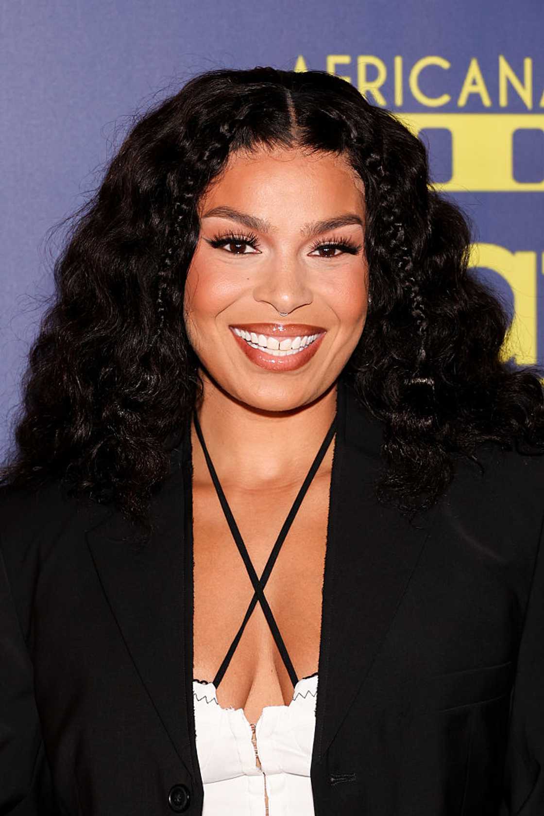 Jordin Sparks in a black blazer over a white strappy top, smiling with long curly hair at the 7th Annual AAFCA TV Honors at The Hollywood Roosevelt, 2025