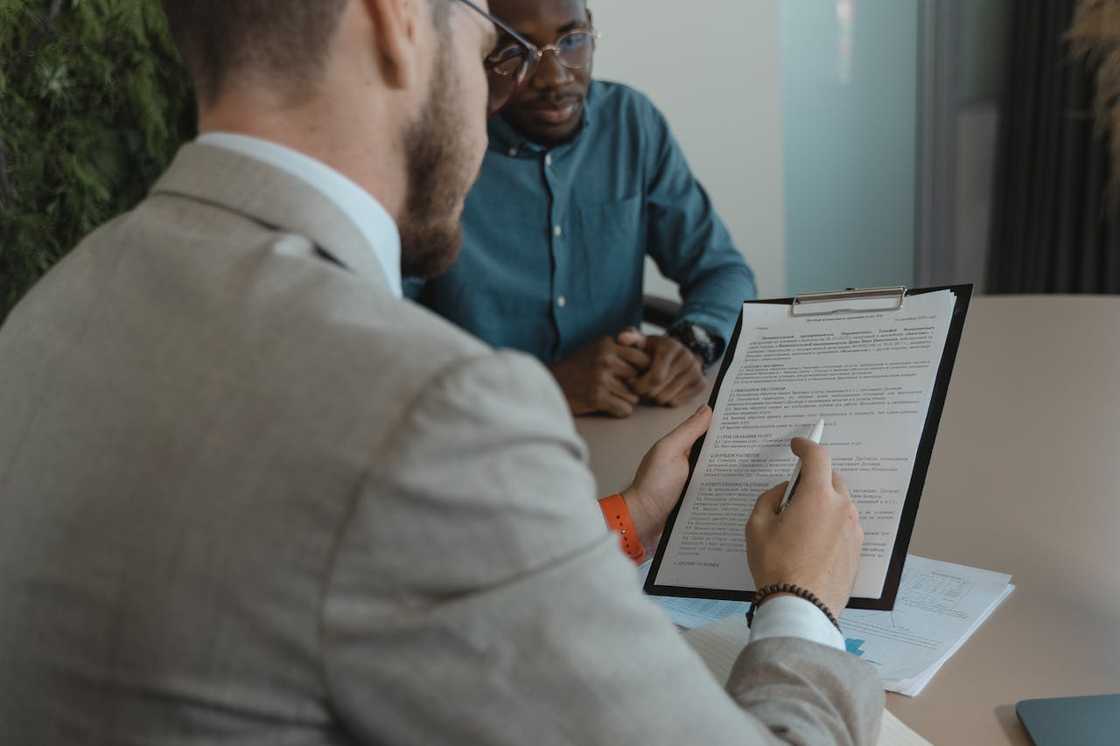 Two men sit at a desk reviewing documents.