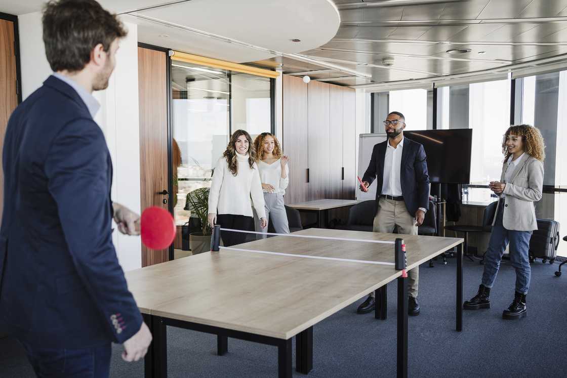 Employees playing table tennis in the office Employees playing table tennis in the office