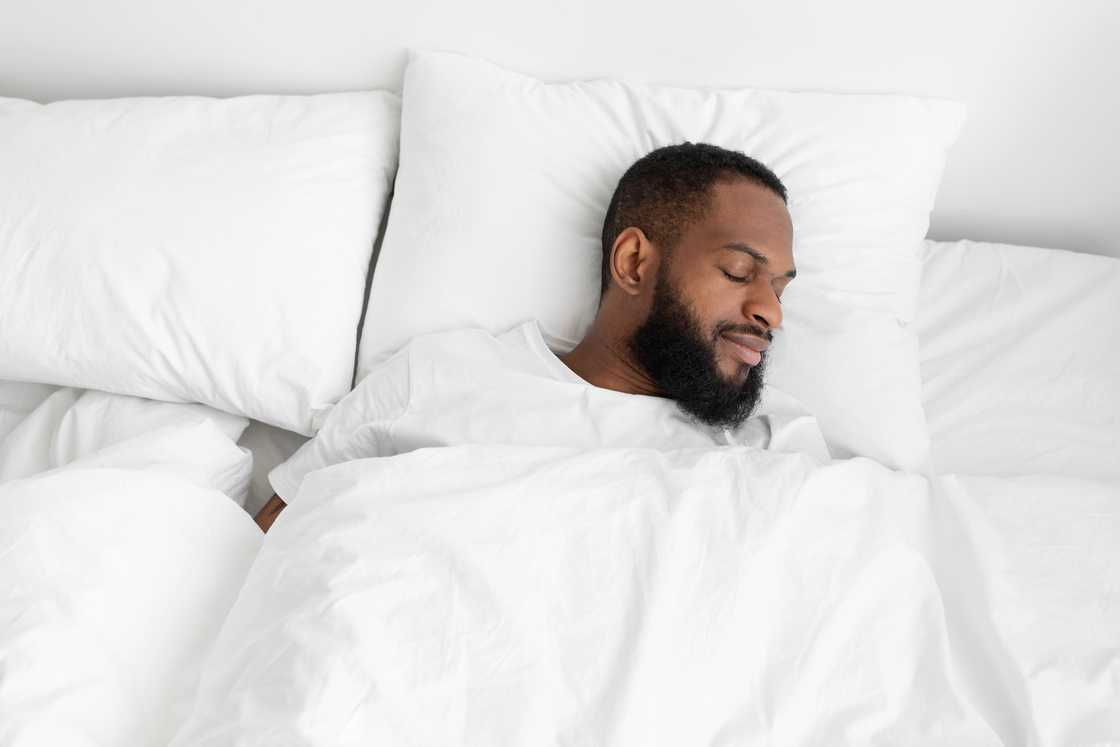 Calm and peaceful bearded man sleeping on bed