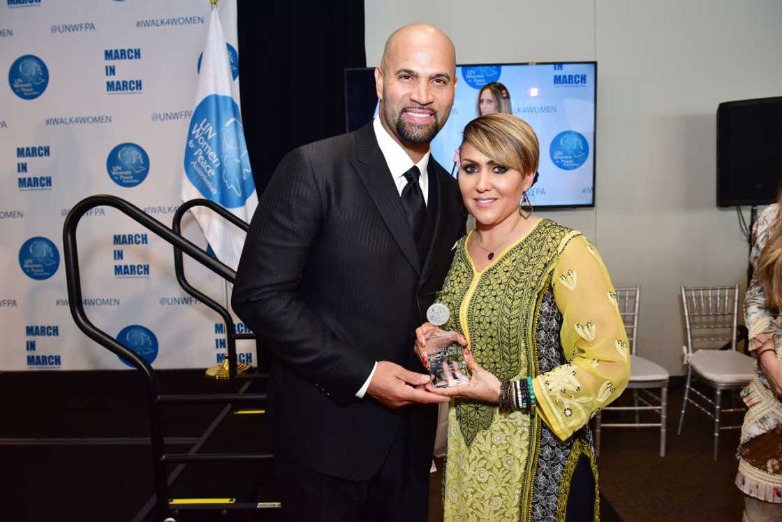 Albert Pujols and Deidre Pujols pose for a photo holding an award Albert Pujols and Deidre Pujols pose for a photo holding an award