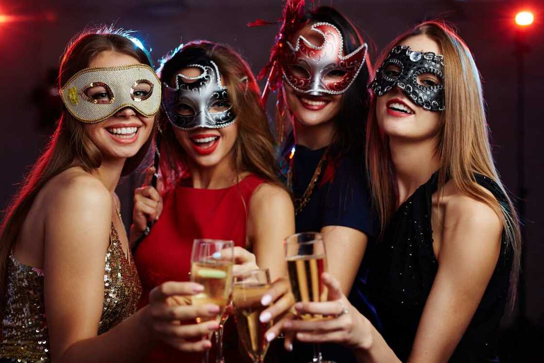 Girls in masks toasting with champagne at party Girls in masks toasting with champagne at party