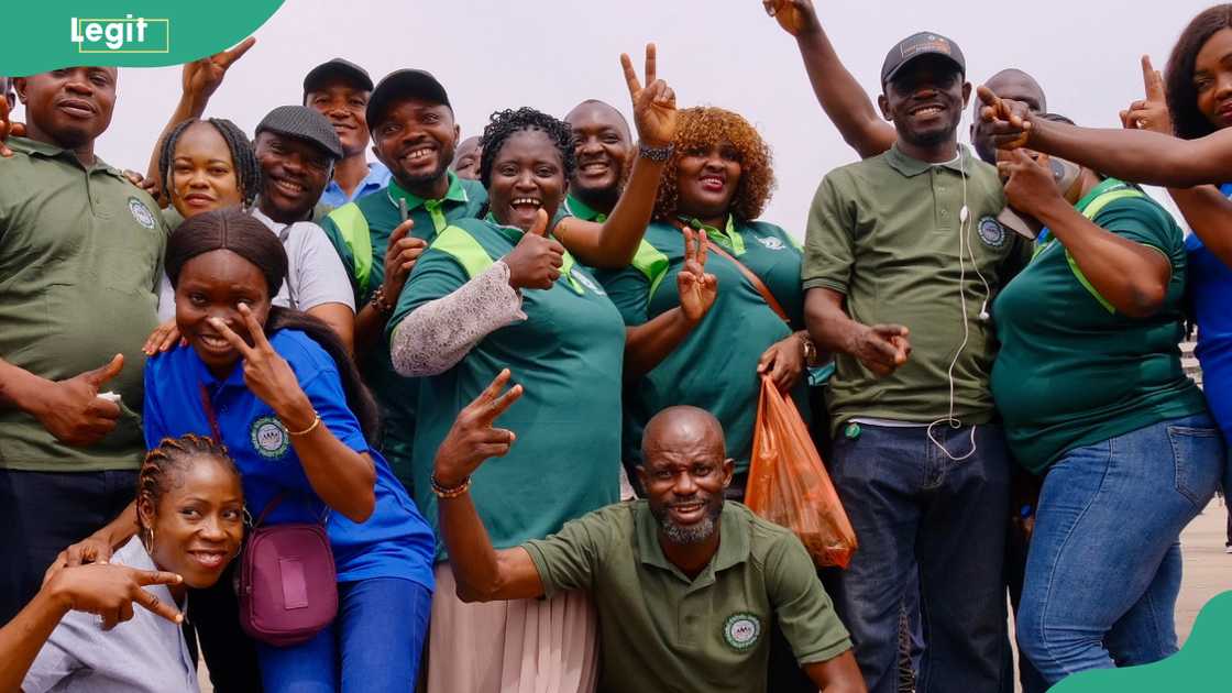 A cheerful group of people posing outdoors, wearing green and blue shirts with the organization’s logo A cheerful group of people posing outdoors, wearing green and blue shirts with the organization’s logo