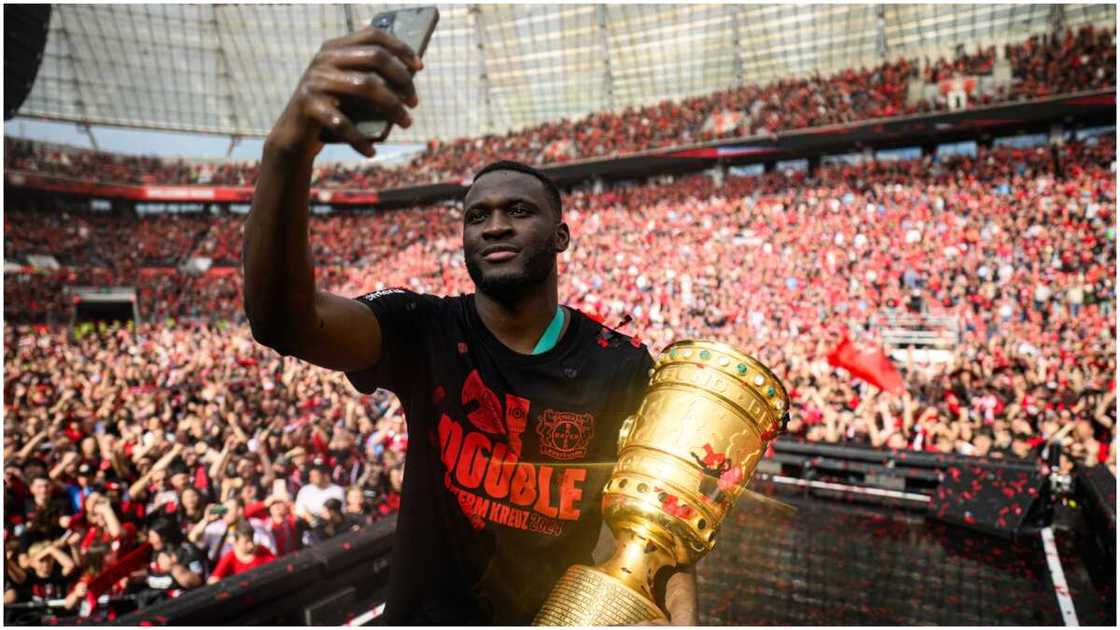 Victor Boniface taking a selfie with Bayer Leverkusen fans.