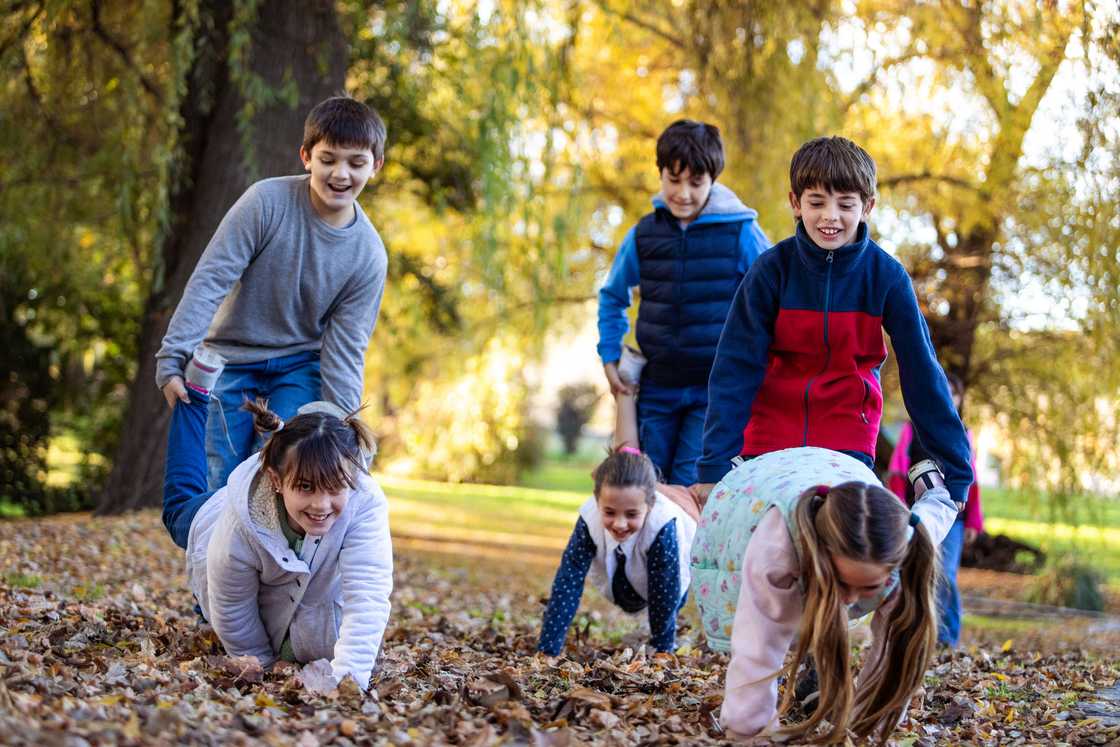 Happy children playing wheelbarrow race outside