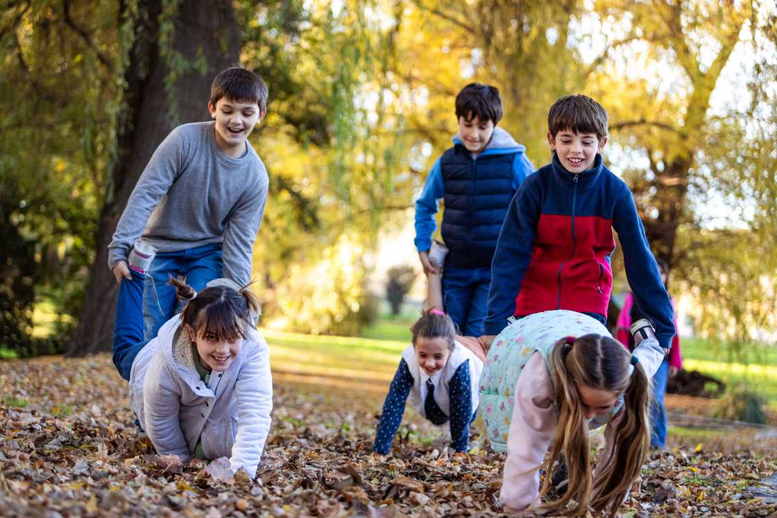 Happy children playing wheelbarrow race outside Happy children playing wheelbarrow race outside