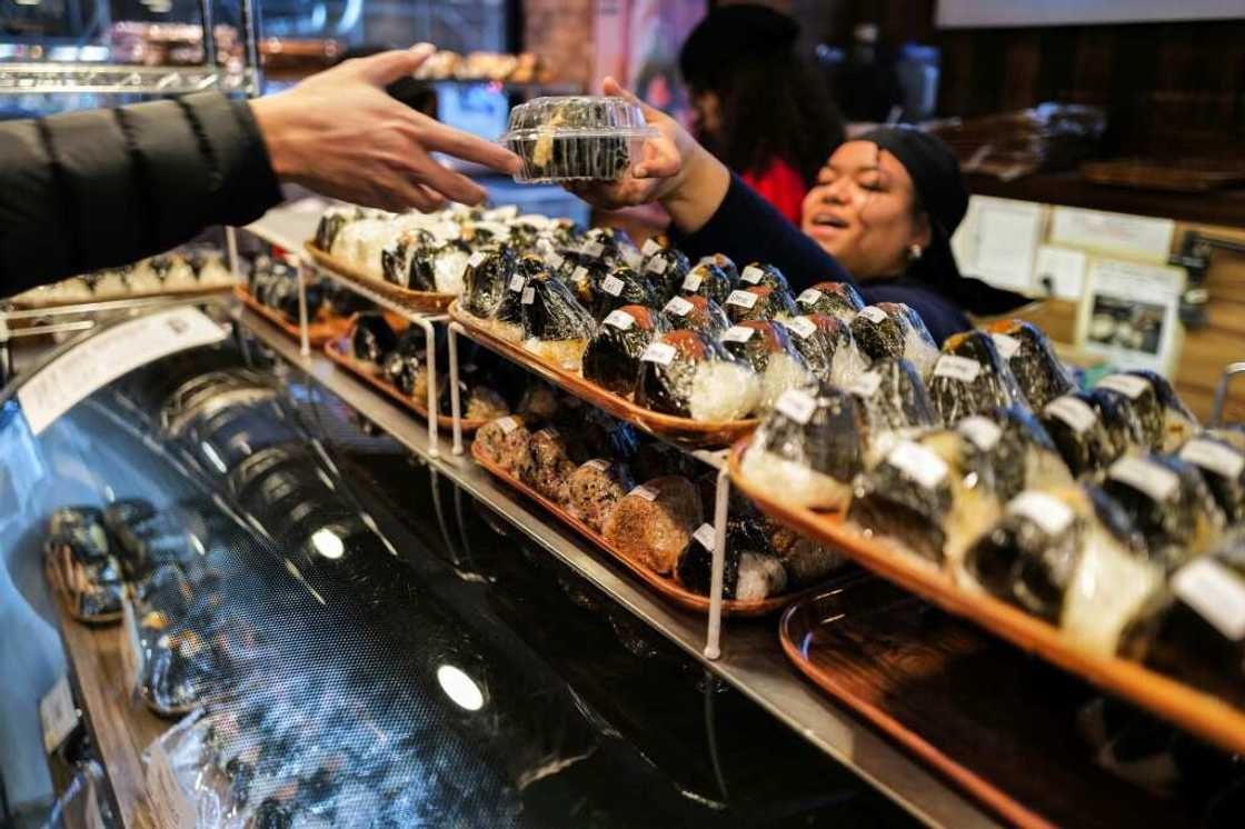 A customer (L) buys a stuffed rice ball, known as "onigiri", at the Omusubi Gonbei shop in Manhattand. A customer (L) buys a stuffed rice ball, known as "onigiri", at the Omusubi Gonbei shop in Manhattand.