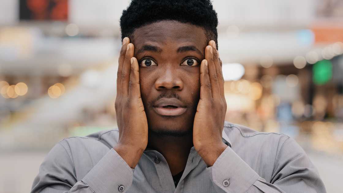 A man holding hands on face, seemingly worried