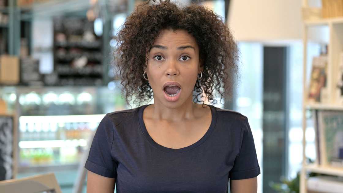 A woman with a shocked face inside a restaurant.