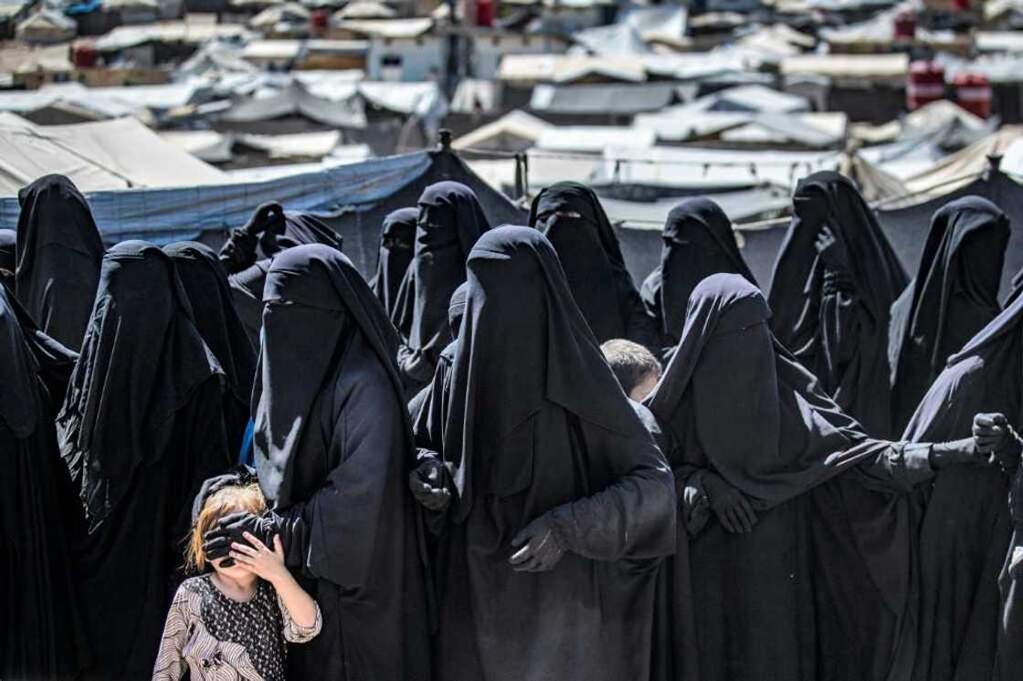 Women and a child queue to receive aid at the Kurdish-run al-Hol camp for relatives of suspected Islamic State group fighters in Syria Women and a child queue to receive aid at the Kurdish-run al-Hol camp for relatives of suspected Islamic State group fighters in Syria